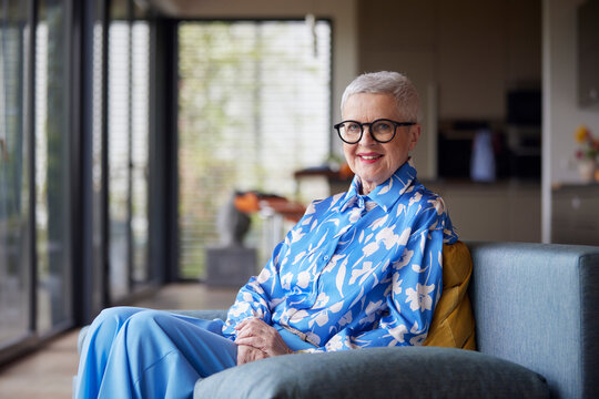Portrait of smiling senior woman sitting on couch at home