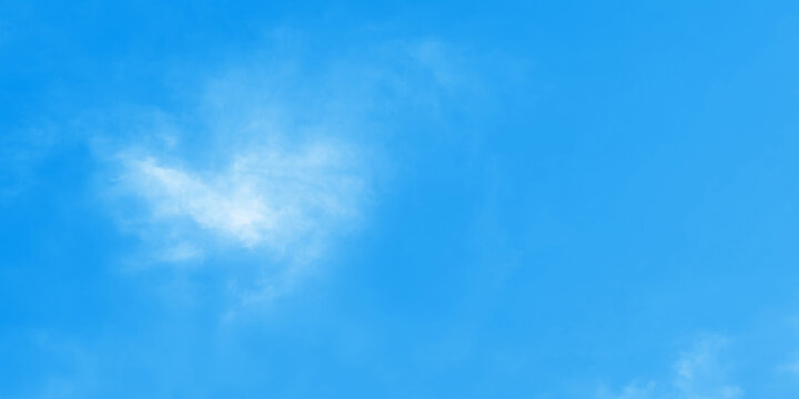 Vibrant, high-key photograph of clear, bright blue sky. Color saturated, cheerful shade of cyan-blue. Sky is largely empty but features few small, wispy, white cirrus clouds concentrated