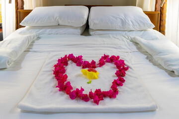 A luxurious four-poster bed adorned with a heart of bougainvillea petals welcomes newlyweds to a tropical honeymoon paradise of elegance, privacy and love