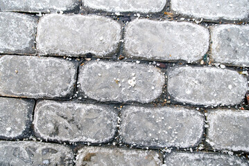Rock salt on pavement closeup, winter maintenance treatment to prevent ice buildup and ensure safe walking on concrete sidewalks in cold urban conditions. Rock salt for winter deicing, selective focus
