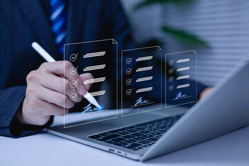 Businessman using digital pen to sign electronic documents on laptop with checklist interface. Concept of e-signature, online contract, digital approval, and paperless business workflow.