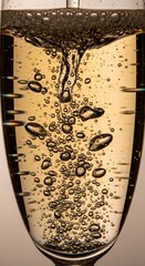 Close-up of bubbles rising in a glass of sparkling beverage with a warm background, showcasing effervescence and carbonation in a detailed manner