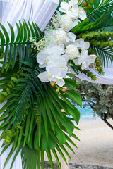 A floral masterpiece of Phalaenopsis aphrodite orchids and tropical leaves captures the essence of island romance