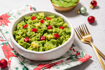Delicious holiday-themed pasta shaped like Christmas trees with vibrant green sauce on a festive plate