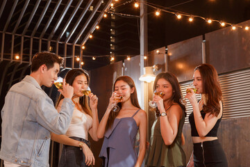 Young Asian man and woman friends celebrating at party, toasting drinks at birthday or festival event. happy people having fun at social gathering, diverse lifestyle concept.