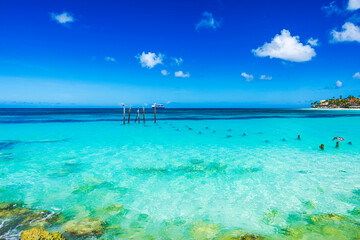 Magnificent view of turquoise Caribbean Sea with rocky shore and distant resort buildings on Eagle...