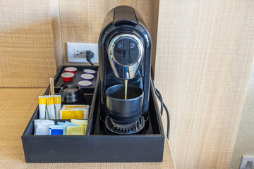 Close up view of Mixpresso coffee machine pouring fresh coffee with tea bags and sugar bags on table in hotel room. Aruba.