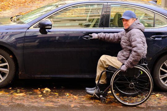 In bad autumn weather, the driver opens the door of his car