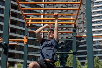 Young man performing a challenging workout on monkey bars at an outdoor street workout park. Focused on fitness, strength, and active lifestyle in an urban setting.