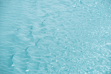 Blue water with ripples on the surface. Defocus blurred transparent blue colored clear calm water surface texture with splashes and bubbles. Water waves with shining pattern texture background.