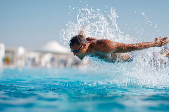 Young caucasian male swimmer performing butterfly stroke in outdoor pool