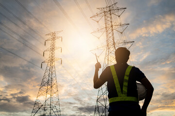 A man in a safety vest stands in front of a power line