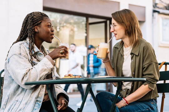 Diverse women friends enjoying coffee outdoors at cafe