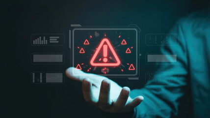 Person holding a digital screen displaying a red warning triangle and data, representing technological alert and risk management