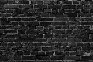 A monochrome image featuring a textured brick wall with visible mortar and uneven brick surfaces
