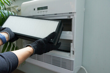 Close-up of a technician's hand holding a new air filter for an air conditioner.
