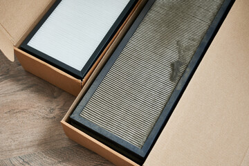 An air filter in a cardboard box on a wooden background. Top view. New and very old air filters.