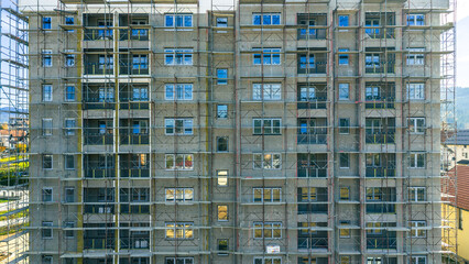 Aerial photo of high-rise residential building under renovation with scaffolding and reflective windows, urban architecture