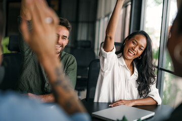 Overjoyed young multiethnic colleagues celebrating shared corporate success or goal achievement