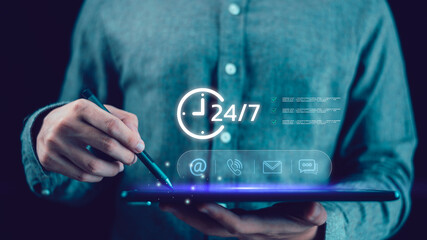 A person using a digital tablet with glowing 24-7 contact icons, symbolizing customer service, online communication, business support, and continuous digital connection in modern technology.