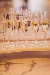Group of elegant champagne flutes filled with bubbly drink on a stylish marble table at a celebration event in a bright and inviting setting