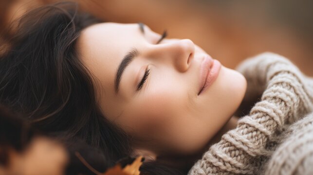 Gracefully resting outdoors, a woman feels the gentle warmth of the sun on her face, surrounded by vibrant autumn leaves. She basks in tranquility while embracing the moment