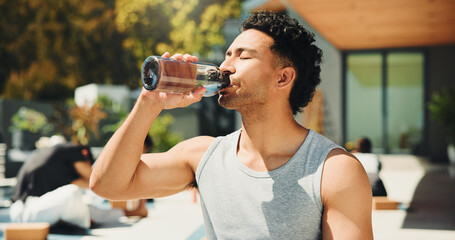 Drinking, outdoor and man with water at fitness class for break, relax or recovery on wellness...