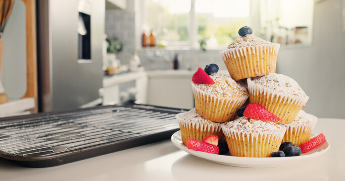Cupcakes, kitchen and baking with fruit for sweet dessert, recipe or pastry creation in home. Empty, baked and muffin with icing sugar, strawberries or blueberries for treat or cake serving on plate