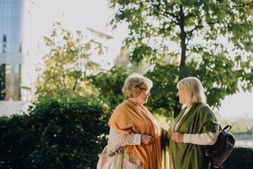 Two senior women talking and smiling in a city park