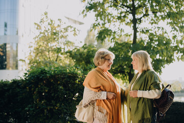 Two senior women talking and smiling in a city park
