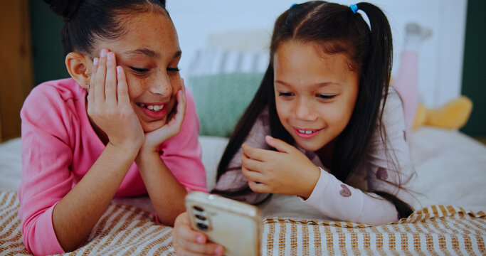 Relax, laugh and kids on phone in bedroom for online entertainment, watching cartoons and movie. Family home, siblings and happy girls on tech for streaming videos, bonding and playing games on bed - Powered by Adobe