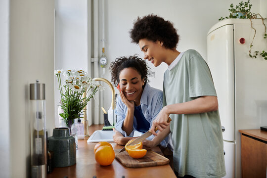 Happy couple sharing joyful moments while cooking in their modern apartment together - Powered by Adobe