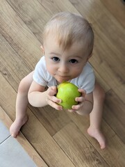A confident baby sitting independently and holding a colorful ball, mastering a new skill.

