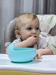A joyful baby happily eating finger food by himself, exploring tastes and textures.

