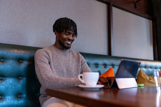 Young man smiling using digital tablet in cafe