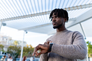 Young black man checking smartwatch in urban setting