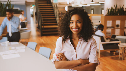 Portrait Of Businesswoman In Modern Office With Colleagues Meeting Around Table In Background