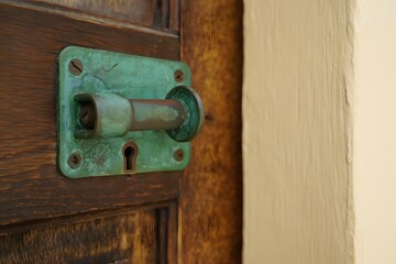 Close up of a weathered green door handle and keyhole on an old wooden door frame