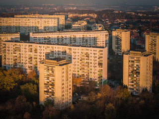 Aerial view of monolithic buildings bathed in the warm glow of the setting sun, casting long shadows over Suchanino's urban tapestry, Gdansk, pomorskie, Poland.