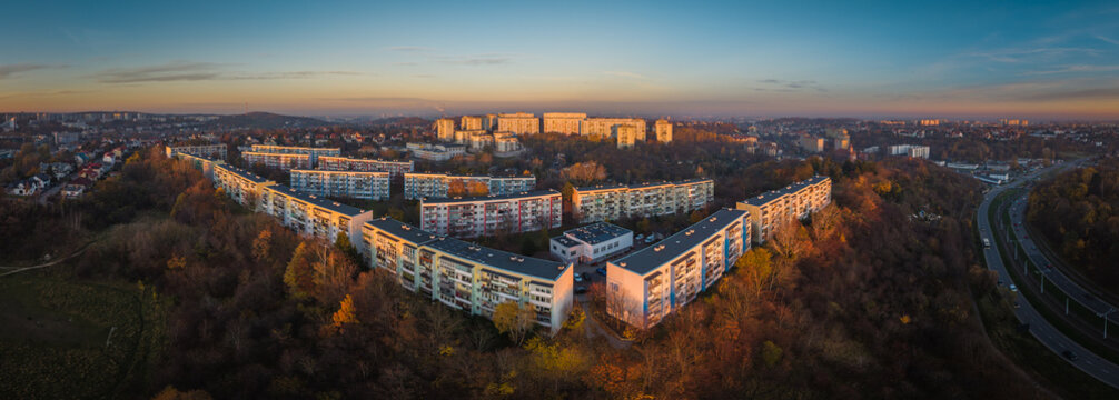 Aerial panoramic view of apartment blocks rise from a hill, bathed in the warm glow of the setting sun, the vibrant hues contrasting with the deep shadows, Gdansk, pomorskie, Poland.