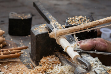 Close-up of artisanal woodturning, with shavings and handcrafted details in a North African market workshop. Traditional woodturner carving wooden pieces by hand and food in a Moroccan souk. 