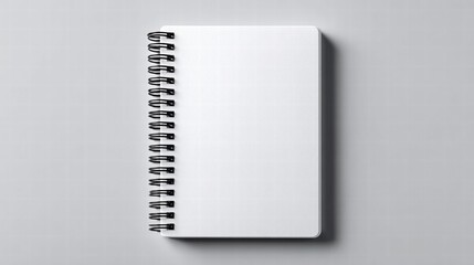 A blank white notebook with a spiral binding lies on a gray surface.
