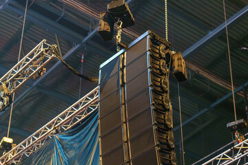 Industrial speakers rigged and suspended in a venue, ready to deliver powerful sound for the upcoming event