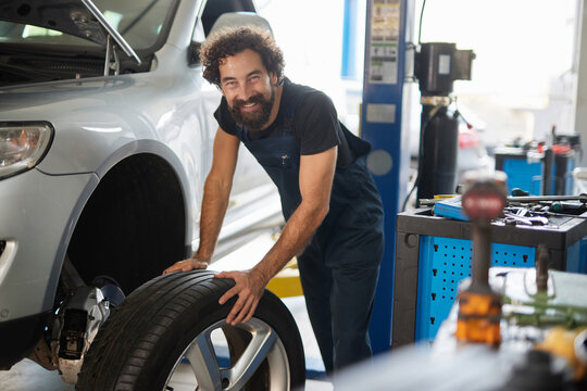 A skilled mechanic is engaged in changing a tire at a bustling garage. The sunlight brightens the space as tools are neatly organized around him.