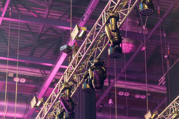 Industrial stage lighting mounted on aluminum frames inside the venue, prepared to illuminate the live performance area