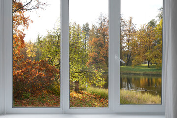  View from the window  on yellow treesin a garden, landscape with autumn forest, window frame.