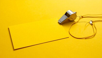 Fototapeta premium A metallic whistle with keychain beside yellow sticky notes on a bright yellow surface—evoking alertness, minimalism, and the choreography of authority, organization, and signal.