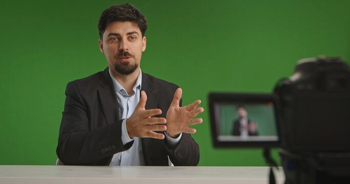 Man presenting in a live streaming studio. Green screen background with professional camera setup.