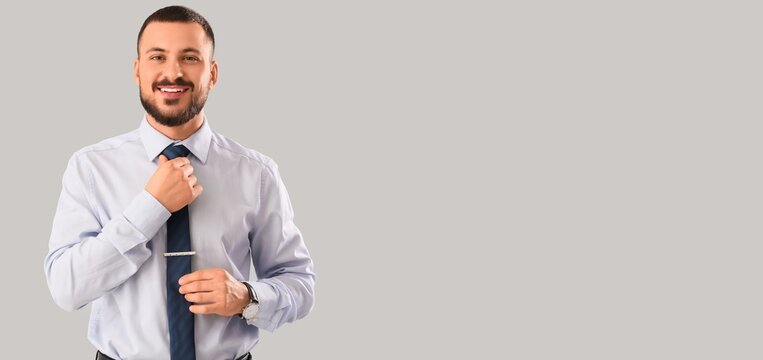 Young man adjusting his tie on light background with space for text - Powered by Adobe