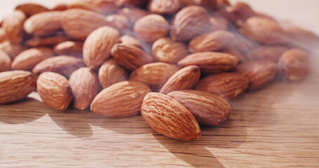 Table, nuts and roasted almonds for diet, vegan meal or healthy snack for nutrition. Kitchen counter, food production and closeup of seeds with smoke for organic benefits, natural vitamins or protein